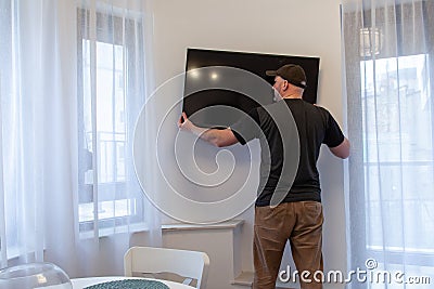 Man mounting new TV on the wall. Man installing television at home Stock Photo