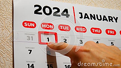 Close-up of a beautiful January page of the wall calendar 2024 and a male finger moves a red cursor to the New year's date Stock Photo