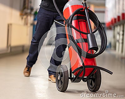 Man moves a wheeled fire-extinguisher. Stock Photo