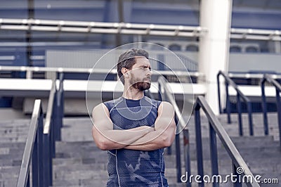 Man muscular fitness coach waiting on stairs stadium entrance background Stock Photo