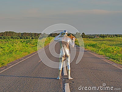 Man musician saxophonist in full body-hugging silver and silver electric suit holding golden alto saxophone, standing on empty Stock Photo