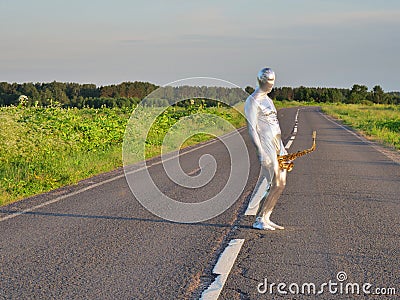 Man musician saxophonist in full body-hugging silver and silver electric suit holding golden alto saxophone, standing on empty Stock Photo