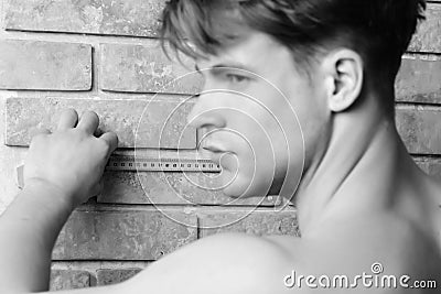 Man with naked body holds yellow self retracting tape measure Stock Photo