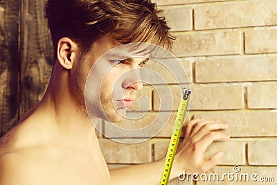 Man with naked body holds yellow self retracting tape measure Stock Photo