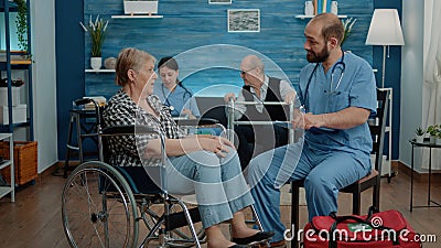 Man nurse consulting elder woman with disability in nursing home Stock Photo