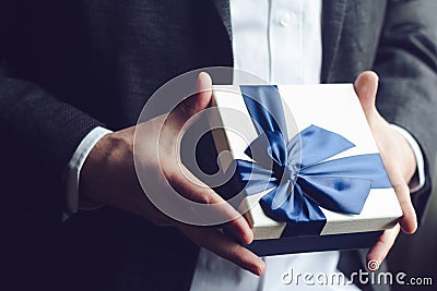 Man offering gift with blue ribbon Stock Photo