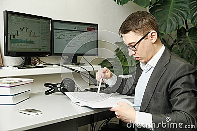 The man in the office for computer monitors studies records in a notebook Stock Photo