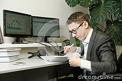 The man in the office for computer monitors studies records in a notebook Stock Photo