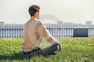 Man in office suit meditate on the green lawn Stock Photo