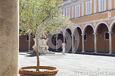 Man in old courtyard with vaults and a statue, in Pisa, Italy. Stock Photo