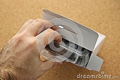 A man opening a box that contains a new hard drive (computer component). Stock Photo