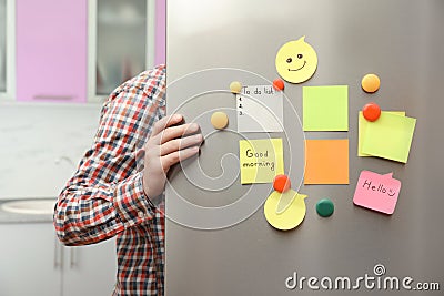 Man opening refrigerator door with paper sheets Stock Photo