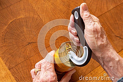 Man opening a tin can with a special opener Stock Photo