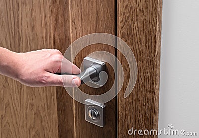 The man opens the door. Close - up of hand and door handle, white wall Stock Photo