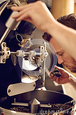 Man operating a modern coffee roasting machine and smelling the Stock Photo