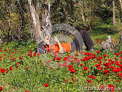 Man in an orange T-shirt is resting in a flowering forest Stock Photo