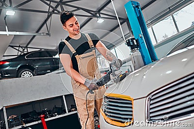Man with orbital polisher in repair shop polishing car Stock Photo