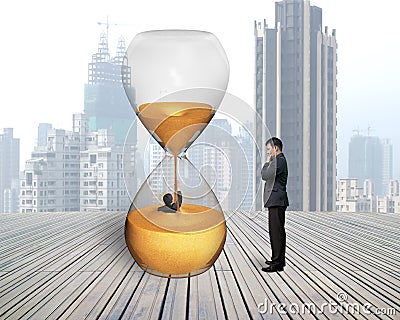 Man oversee businessman flooded in hourglass Stock Photo