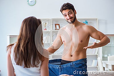 Man in oversized pants in weight loss concept with girlfriend wi Stock Photo