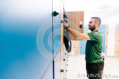 Man packing his gym bag into a blue locker Stock Photo