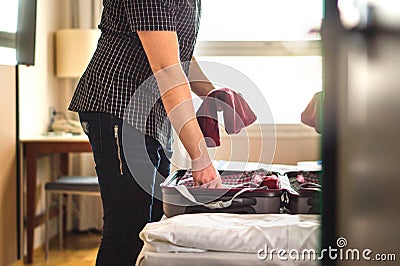 Man packing suitcase for vacation. Person putting clothes to bag Stock Photo
