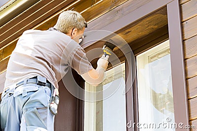 Man with paintbrush painting wooden house exterior Stock Photo