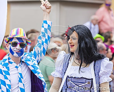 A man in with painted face and blue and white squares and a drag queen attending the Gay Pride in Munich Editorial Stock Photo