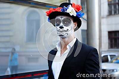 A man with a painted face of a skeleton, a dead zombie, in the city during the day. day of all souls, day of the dead, halloween, Stock Photo