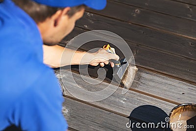 Man painting wooden terrace planks with wood protection oil Stock Photo