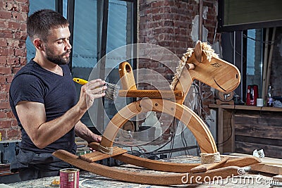 Man paints a wooden toy Stock Photo