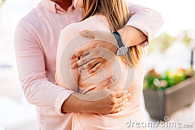 Man in a pastel shirt and a wristwatch hugs a woman in an orange blouse. Close-up Stock Photo