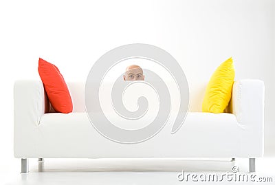 Man peeping from behind sofa Stock Photo