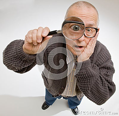 Man peering through magnifying glass Stock Photo