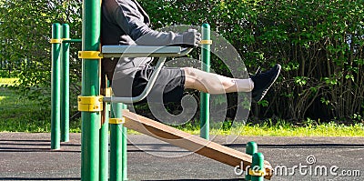 Man performing an exercise, on uneven bars, outdoors, side view Stock Photo