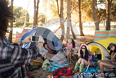 Man photographing smiling friends through mobile phone Stock Photo