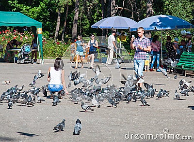 Man photographing woman feeds pigeons Editorial Stock Photo