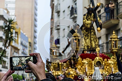 A man photographs with his mobile phone the Procession of Jesus the Nazarene in Huelva, Spain Stock Photo