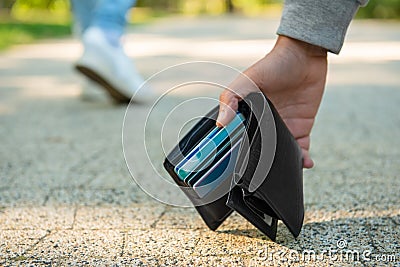 Man picking lost wallet from ground outdoors, closeup. Space for text Stock Photo