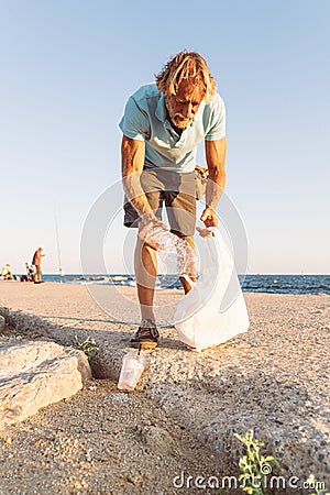 Man picking up plastic at the beach Stock Photo