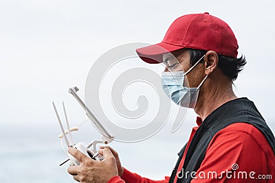 Man piloting drone while wearing face mask to avoid corona virus spreading Stock Photo
