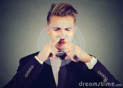 Man pinches nose with fingers looks with disgust something stinks bad smell. Stock Photo