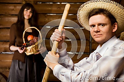 Man with pitchfork and in hat, woman with basket Stock Photo