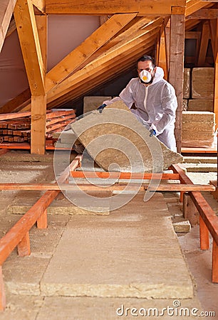 Man places rockwool thermal insulation between wooden scaffolding Stock Photo