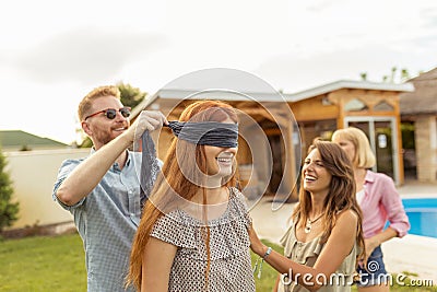 Man placing blindfold over woman`s eyes while playing blind man`s buff Stock Photo