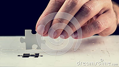 Man placing the last piece in the jigsaw puzzle Stock Photo