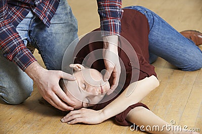 Man Placing Woman In Recovery Position After Accident Stock Photo