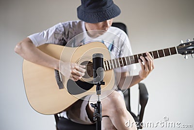 Man playing acoustic guitar through front microphone. Stock Photo