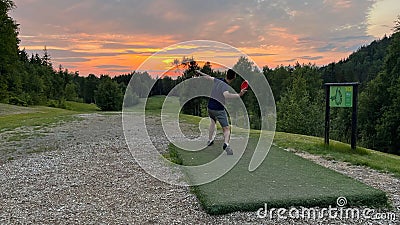 Man playing disc golf at the Krokhol Disc Golf Course in Norway against a golden sunset Stock Photo