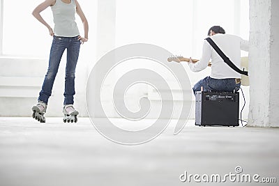 Man Playing Electric Guitar With Woman Wearing Inline Skate In W Stock Photo