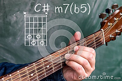 Man playing guitar chords displayed on a blackboard, Chord C minor 7b5 Stock Photo